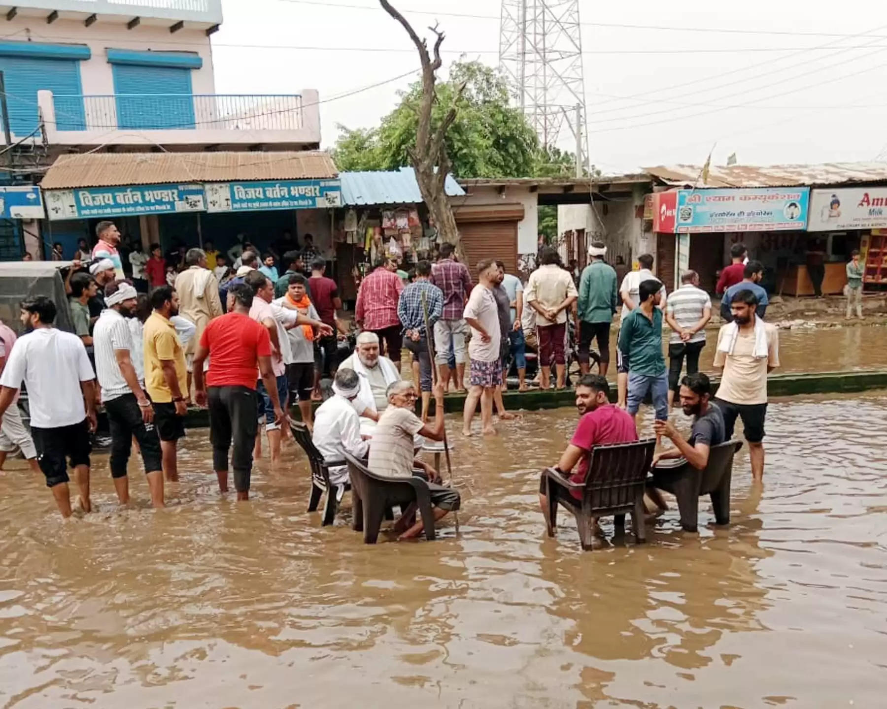 गुरुग्राम: सडक़ पर भरे बरसाती पानी में दुकानदार कुर्सी डालकर धरने पर बैठे